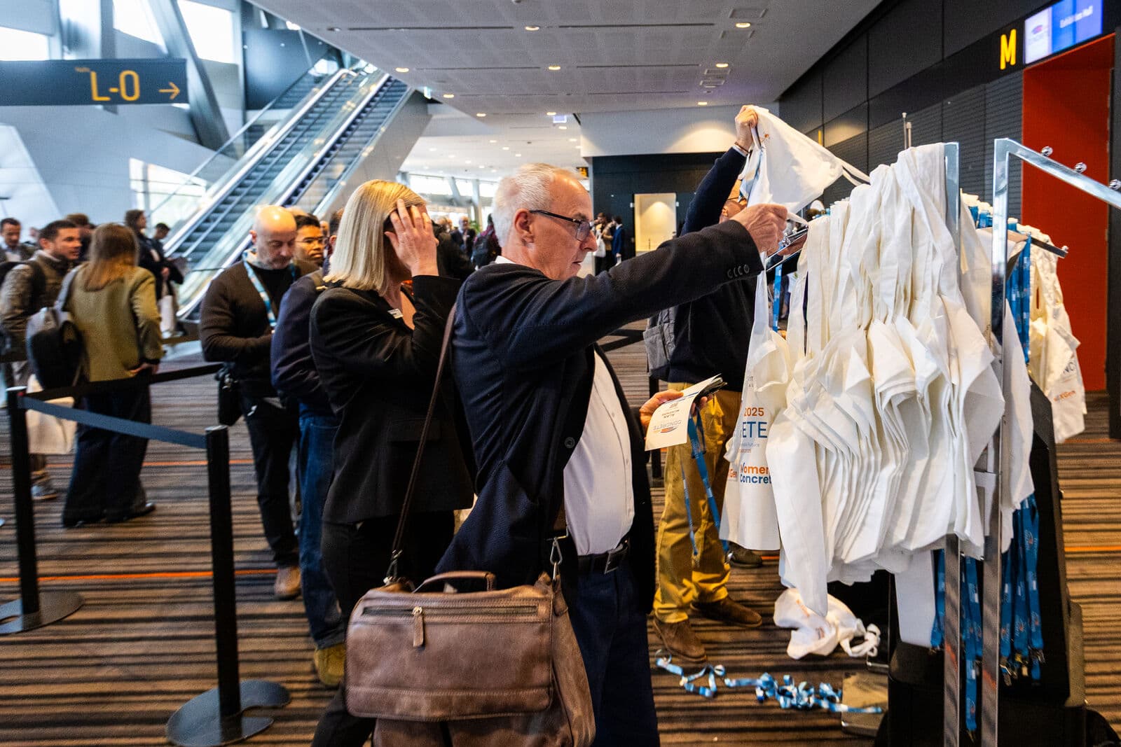 Delegates collect conference bags and lanyards in a busy convention centre foyer