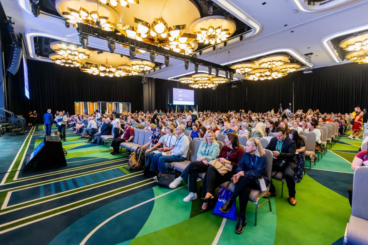 Hundreds of delegates seated in a large ballroom for a plenary session